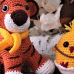 Crochet stuffed tiger and chick among autumn leaves, perfect for seasonal decor.