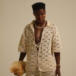 Fashion-forward individual in crochet attire with a seashell, showcasing modern style.