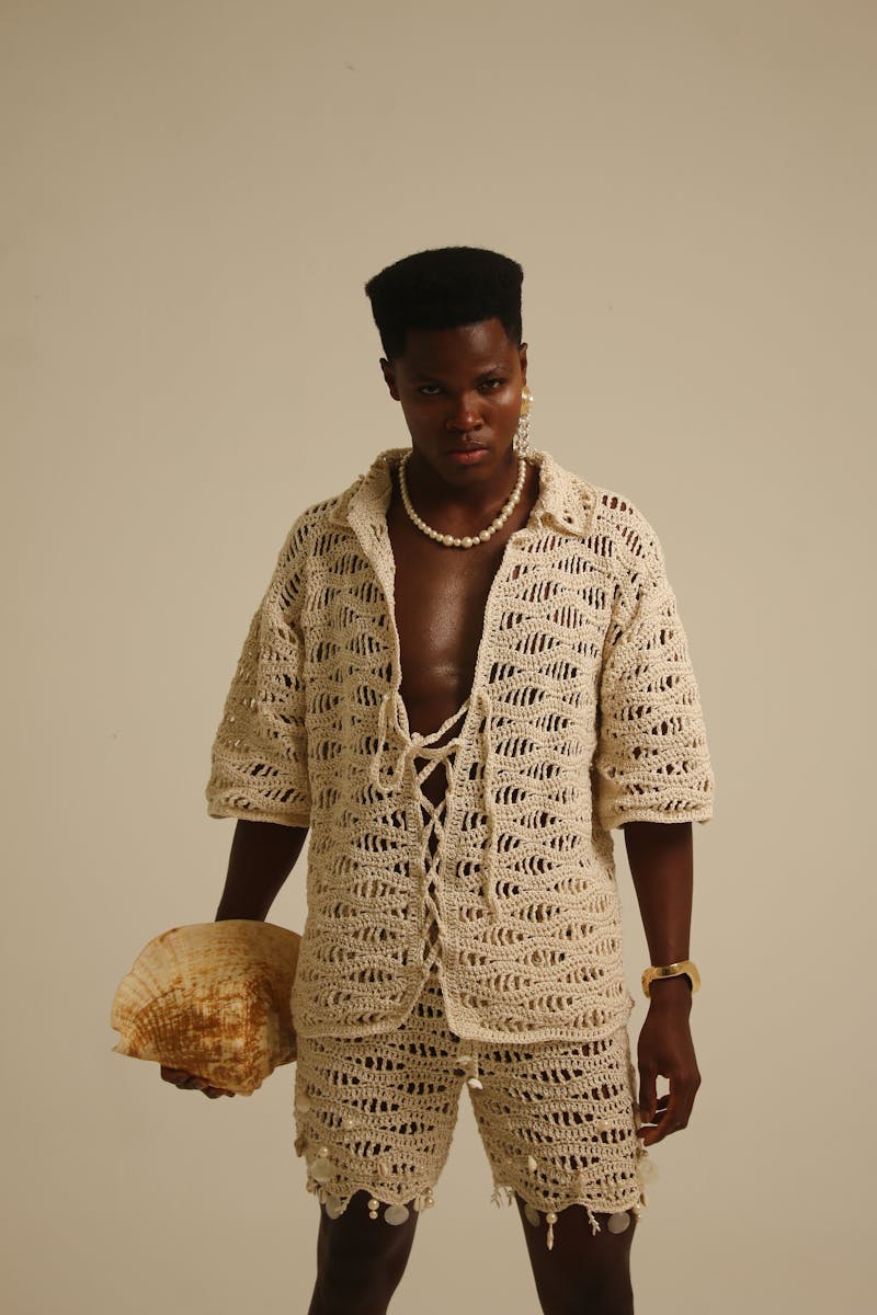 Fashion-forward individual in crochet attire with a seashell, showcasing modern style.